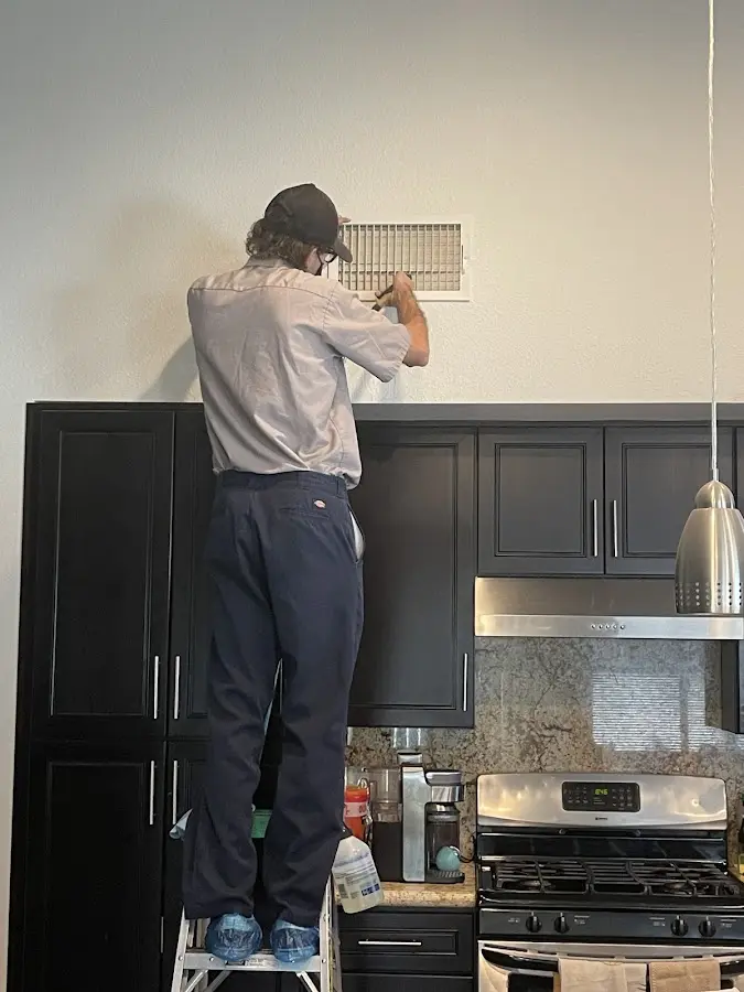 Technician inspecting an air vent during HVAC service in Glenvar Heights